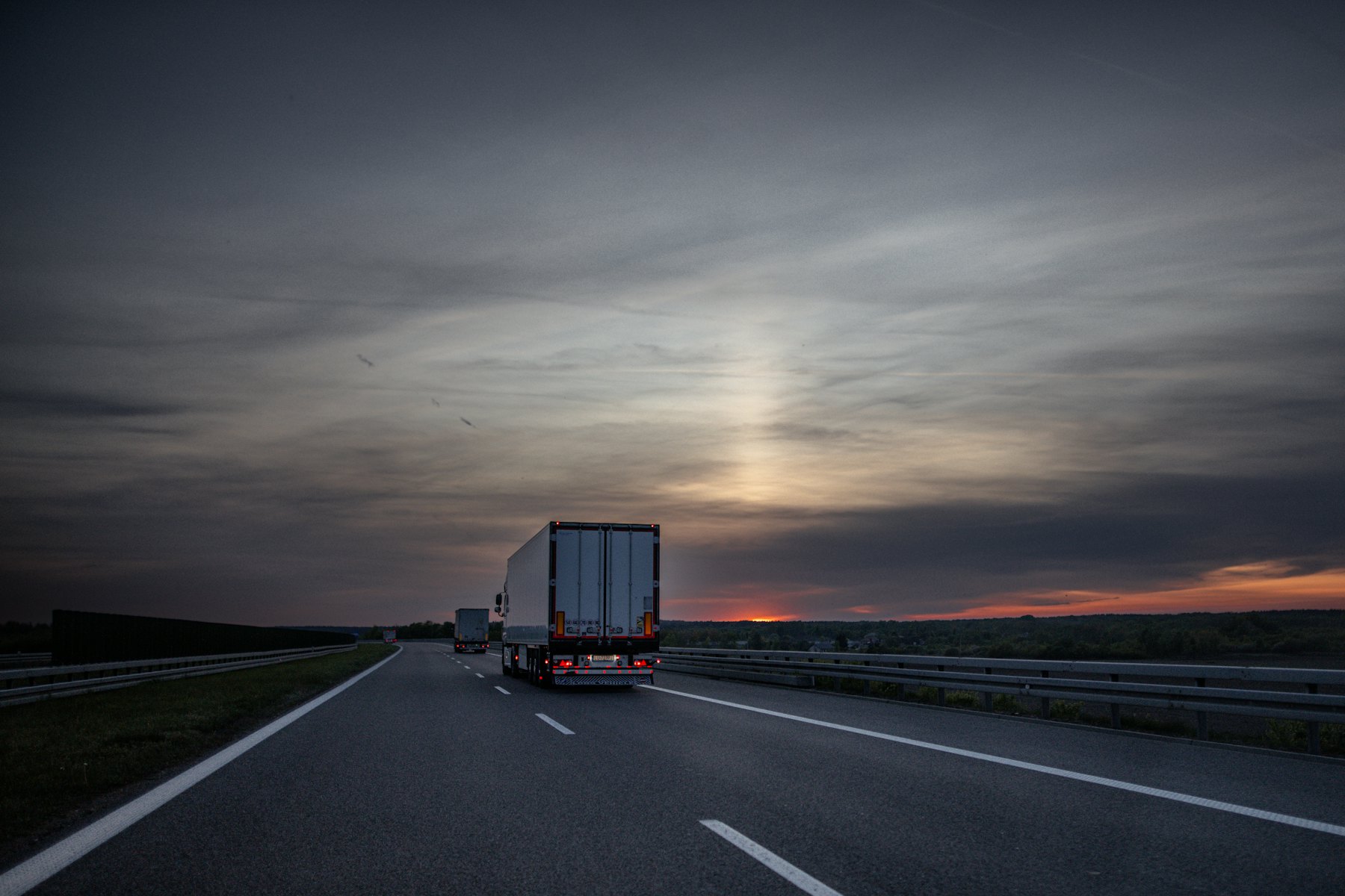 Tractor-trailer driving down an open highway at sunset
